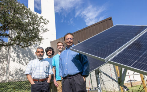 Researchers stand by solar panels for an agrivoltaics project, merging farming and solar power.