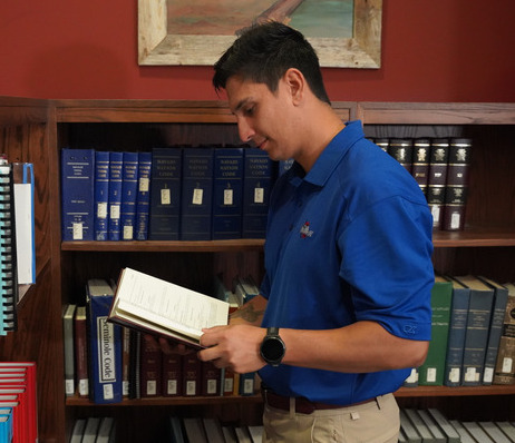 Law student reading a book in the College of Law library.