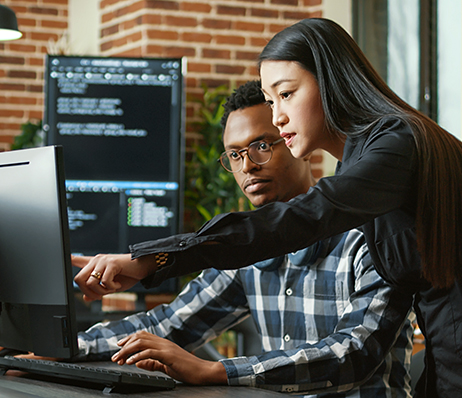 Photograph of two people examining something on a computer monitor