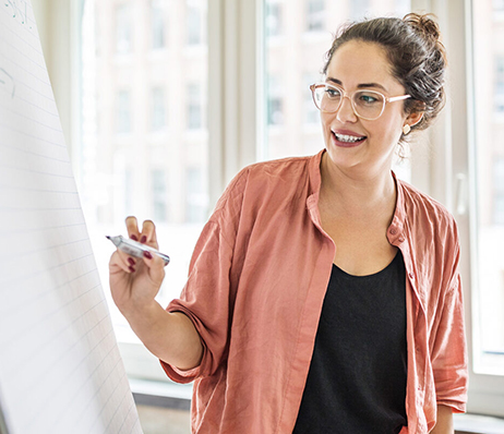 Photograph of a woman making notes on a presentation board with a marker