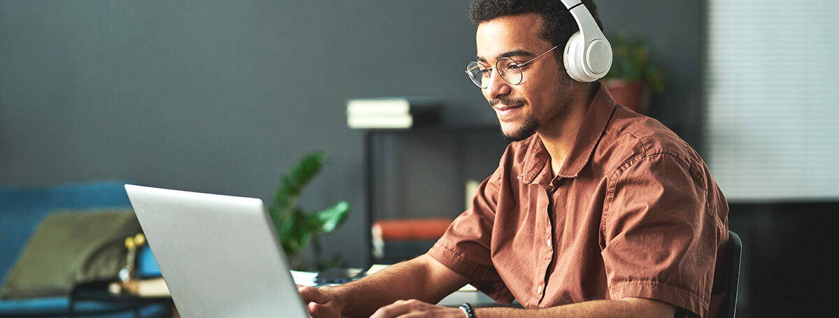 Photograph of a students looking at a laptop and wearing headphones