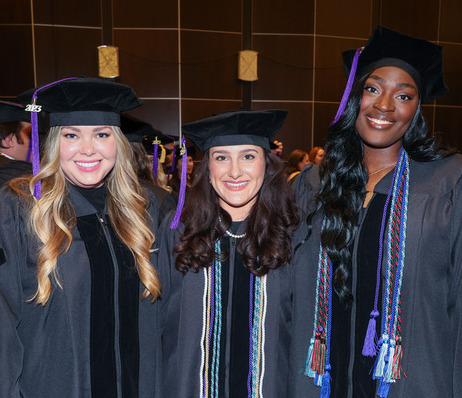 Photograph of three TU Law graduates wearing regalia during their hooding ceremony