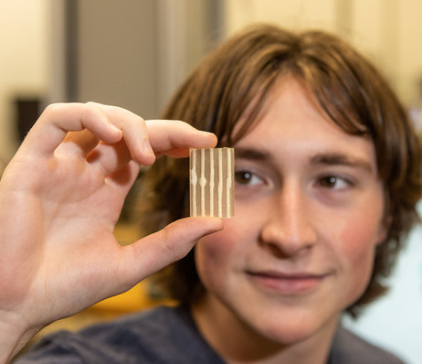 Photograph of a TU student holding a small sample of material between two fingers