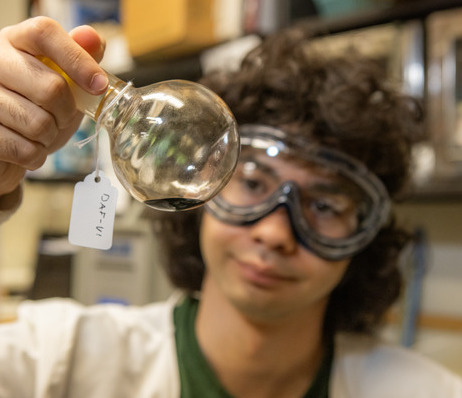 Photograph of a student holding a beaker and wearing safety goggles in a lab